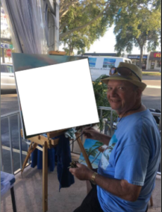 Lloyd Dobson Artist sitting on Monk's Steamer Bar patio with a blank canvas getting ready to paint live