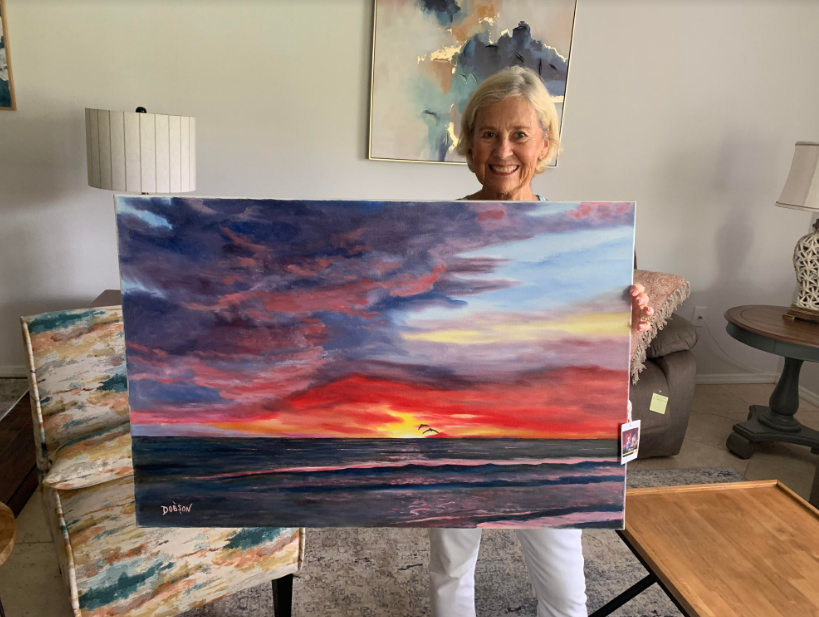 Art collector Judy Hammond holding an oil painting by Lloyd Dobson Artist