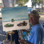 Lloyd Dobson Artist sitting at easel painting commission painting of cars on Siesta Key Beach