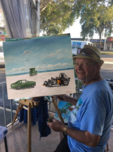Lloyd Dobson Artist sitting at easel painting commission painting of cars on Siesta Key Beach