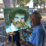 Lloyd Dobson Artist at Monk's Steamer Bar on their patio sitting at an easel painting