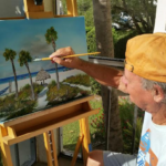 Lloyd Dobson Artist sitting at easel painting a coastal scene